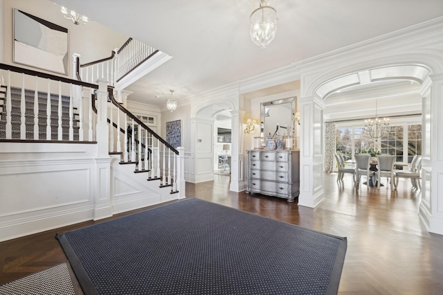 entrance foyer featuring a chandelier, a decorative wall, and ornate columns