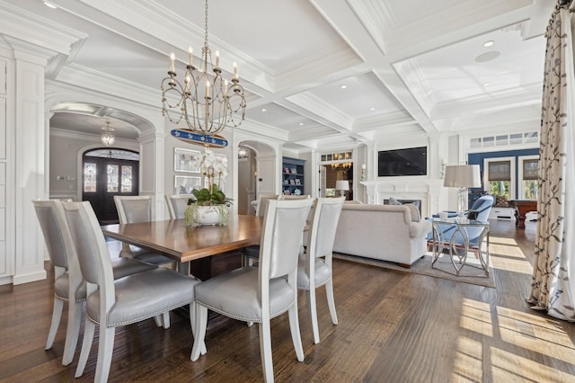 dining space with a decorative wall, arched walkways, beamed ceiling, a notable chandelier, and dark wood-type flooring