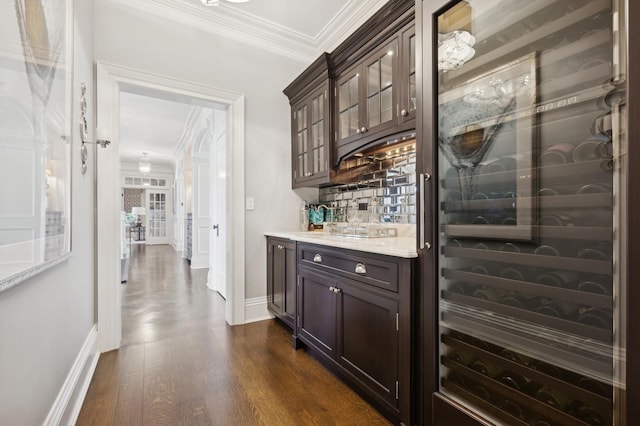 bar featuring wine cooler, crown molding, bar area, baseboards, and dark wood finished floors