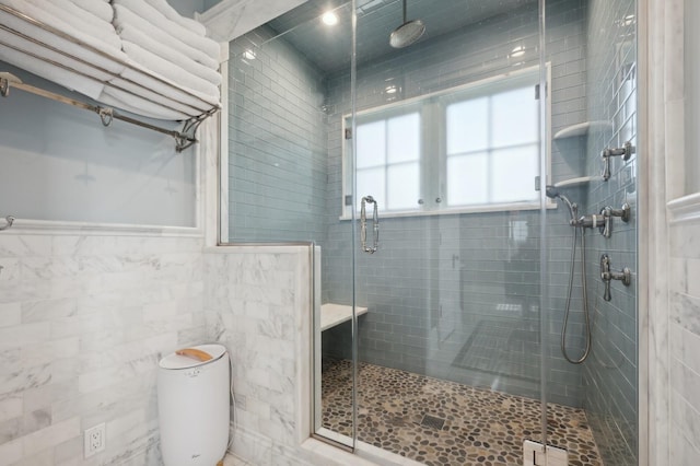 bathroom featuring a shower stall, toilet, and tile walls
