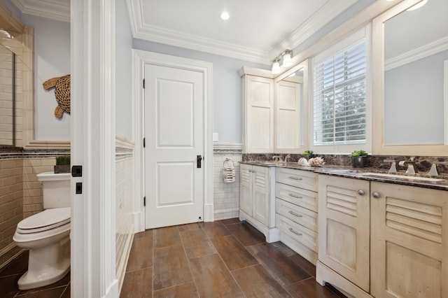 bathroom featuring double vanity, tile walls, a wainscoted wall, and a sink