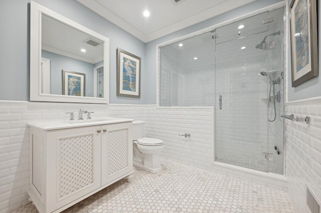 bathroom with wainscoting, crown molding, and tile walls