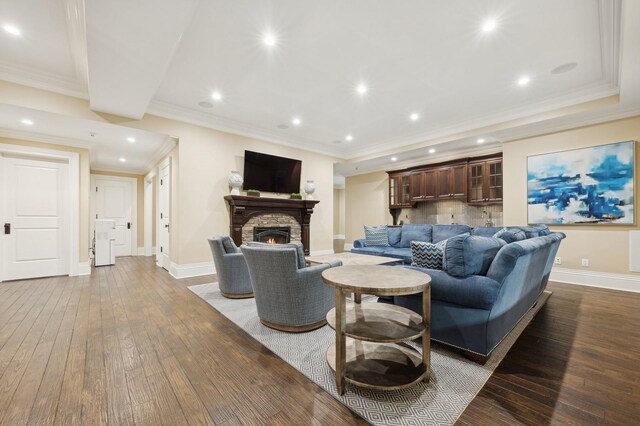 living area featuring recessed lighting, hardwood / wood-style floors, a fireplace, baseboards, and crown molding