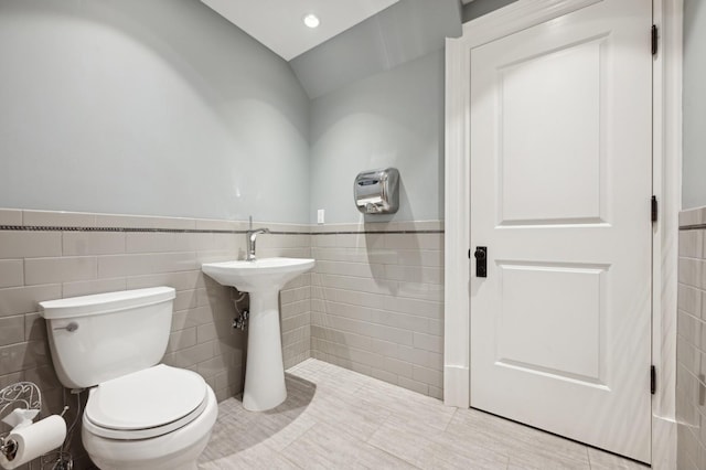 bathroom featuring tile walls, vaulted ceiling, and toilet