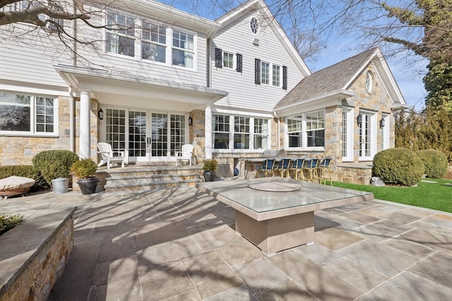 back of property featuring stone siding, french doors, and a patio area