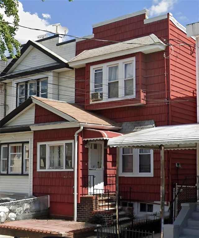 multi unit property with a shingled roof and a fenced front yard