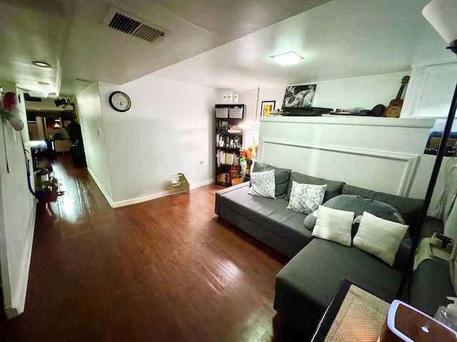 living area with baseboards, visible vents, and wood finished floors