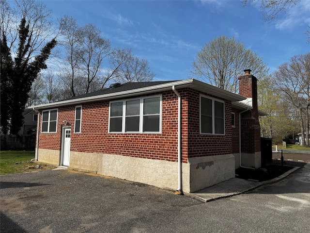 view of side of home with a chimney and brick siding