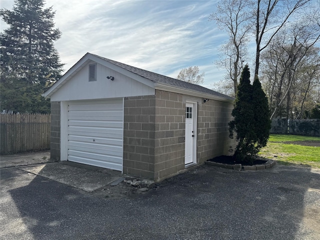 detached garage featuring fence and driveway