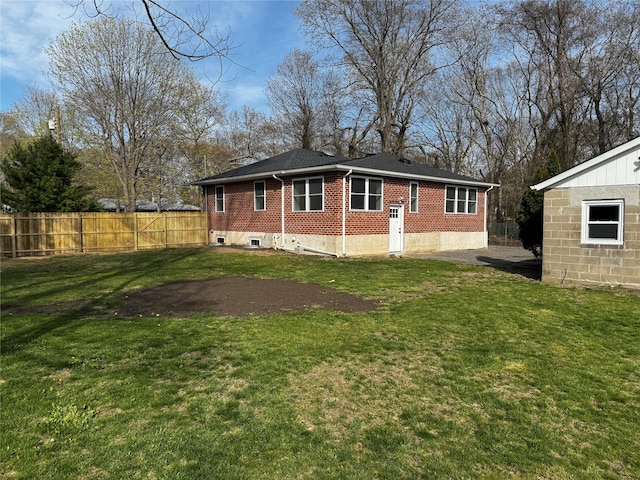 back of property with brick siding, a lawn, and fence