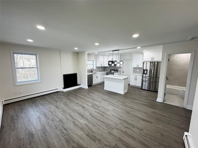 kitchen with open floor plan, a baseboard radiator, appliances with stainless steel finishes, and light countertops