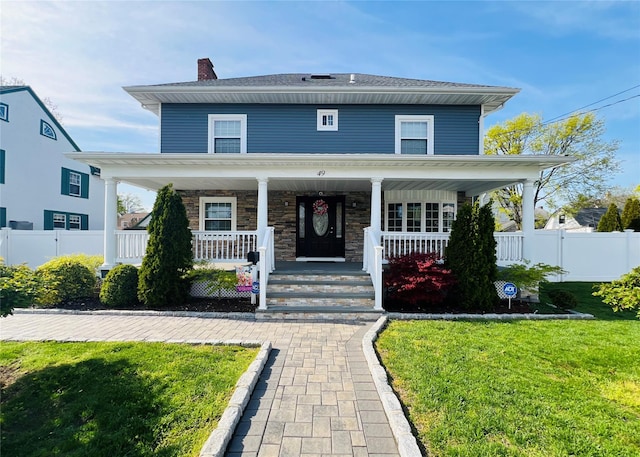 american foursquare style home with a chimney, a front lawn, fence, and a porch