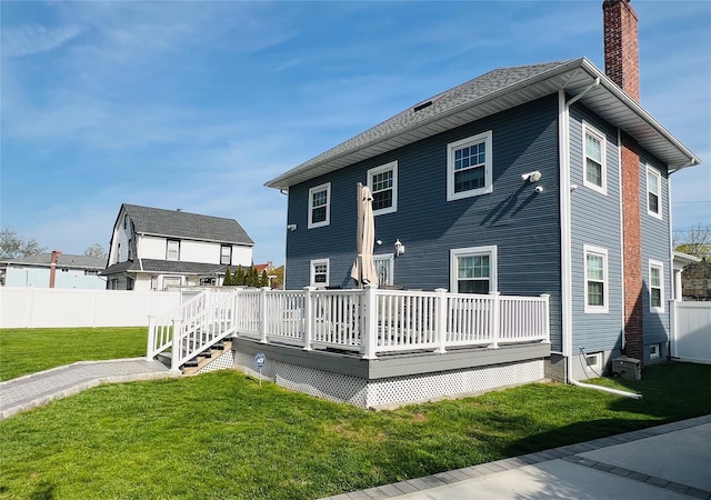 rear view of property with fence, a chimney, a yard, and a deck