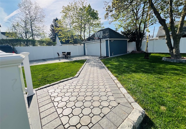 view of yard with a garage, a fenced backyard, an outdoor structure, and a patio