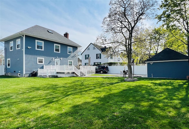 rear view of property featuring a wooden deck, a lawn, a chimney, and fence
