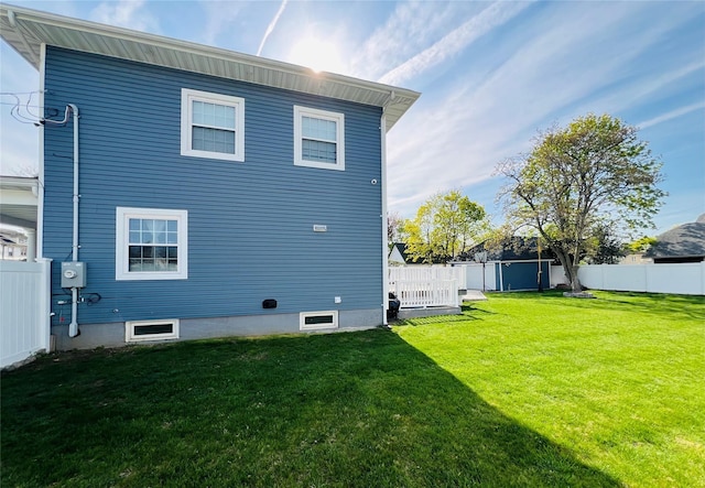 rear view of property featuring a fenced backyard, an outdoor structure, a yard, and a storage shed