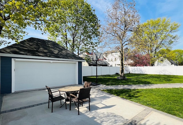 view of patio / terrace featuring a detached garage, an outbuilding, outdoor dining area, and fence