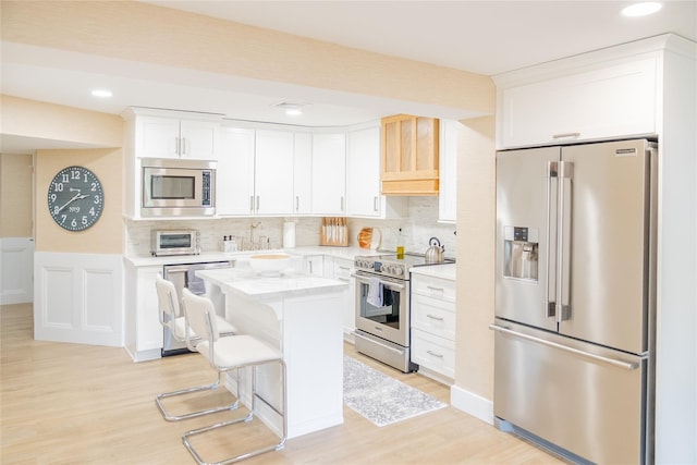 2 Spring Hollow Rd, Centerport, NY 11721 - kitchen featuring stainless steel appliances, light countertops, a center island, light wood finished floors, and white cabinetry