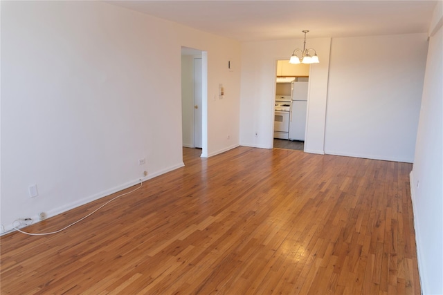 unfurnished room featuring baseboards, a notable chandelier, and light wood-style flooring