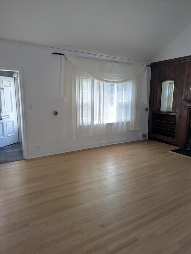 unfurnished living room with baseboards, visible vents, lofted ceiling, and light wood-type flooring