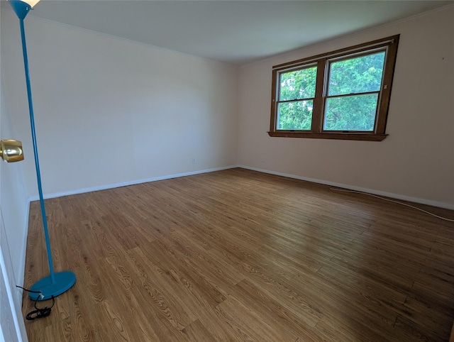 unfurnished room with baseboards, crown molding, and wood finished floors