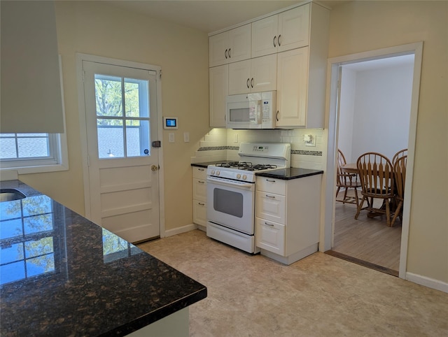 kitchen with white appliances, baseboards, light floors, white cabinets, and tasteful backsplash