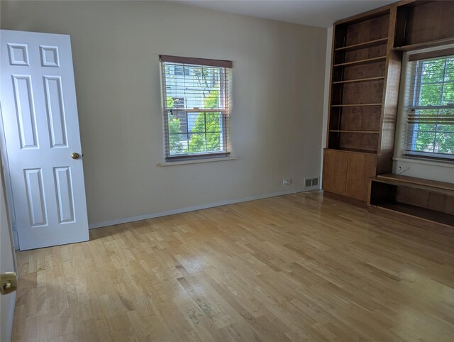 unfurnished bedroom with visible vents, light wood-style flooring, and baseboards
