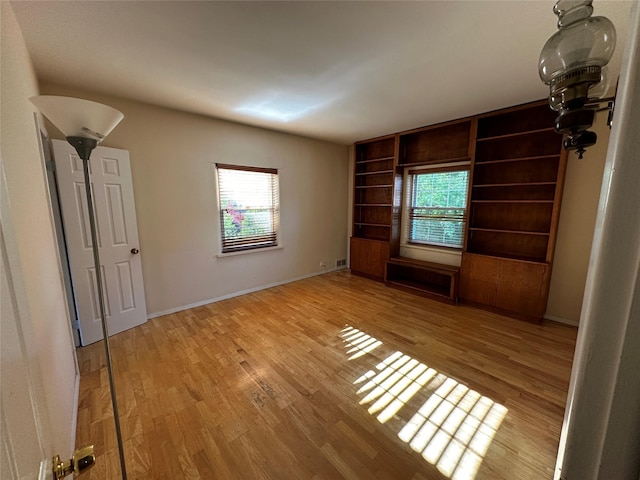 interior space with baseboards, built in shelves, and light wood-style flooring