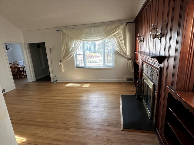 unfurnished living room with baseboards, a glass covered fireplace, light wood-style flooring, and visible vents