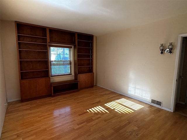 spare room featuring visible vents, light wood finished floors, and baseboards