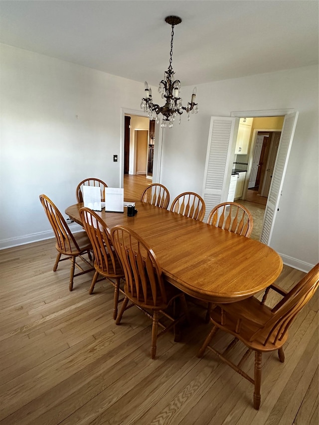 dining room featuring baseboards, a notable chandelier, and light wood-style flooring