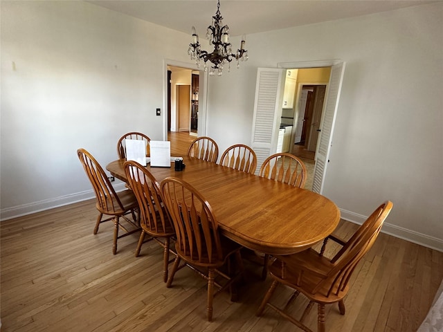 dining space with baseboards, a notable chandelier, and light wood-style floors