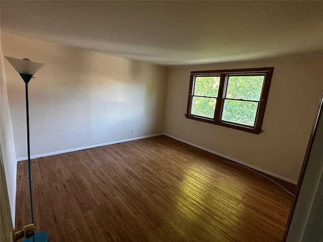 spare room with baseboards and dark wood-style floors