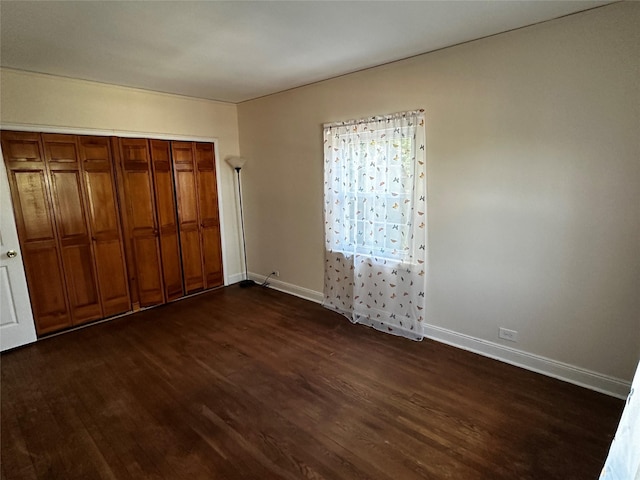 unfurnished bedroom featuring dark wood-type flooring and baseboards