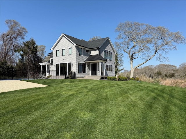 back of house with fence, a standing seam roof, and a yard