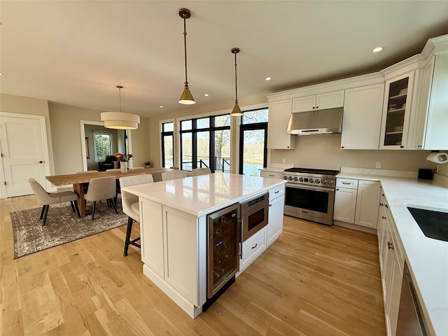 kitchen with wine cooler, plenty of natural light, stainless steel appliances, and under cabinet range hood