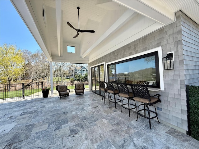 view of patio featuring ceiling fan, fence, outdoor dry bar, and visible vents