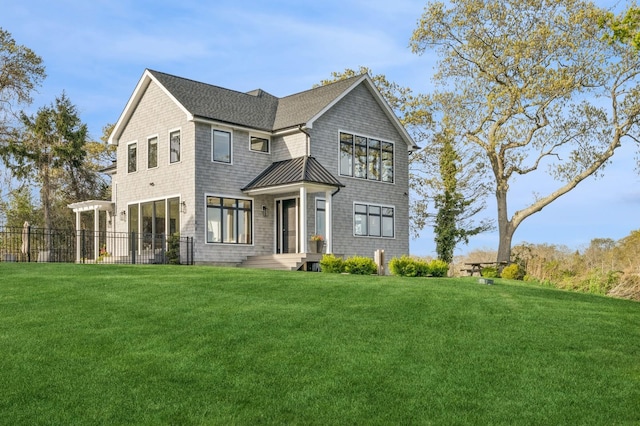 view of front of property with fence, metal roof, a front yard, and a standing seam roof