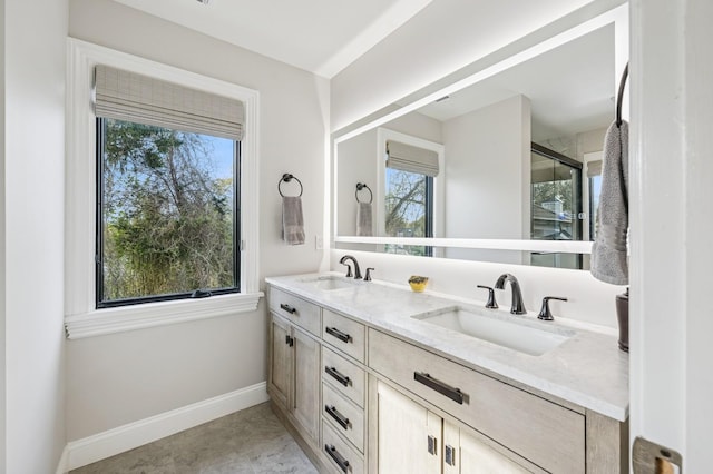 bathroom featuring a sink, baseboards, a shower with door, and double vanity