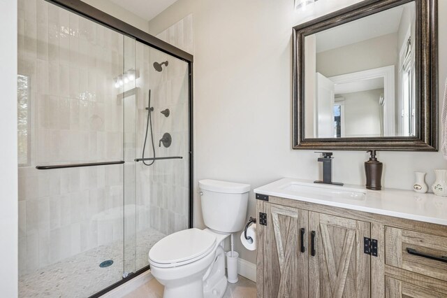 bathroom with vanity, baseboards, a stall shower, and toilet
