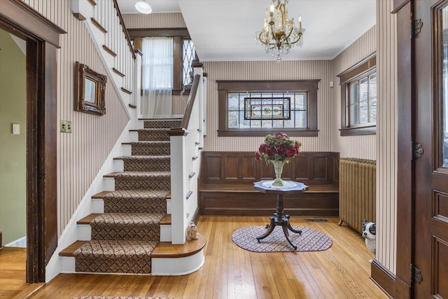 foyer entrance with stairway, wood-type flooring, a wealth of natural light, and wallpapered walls