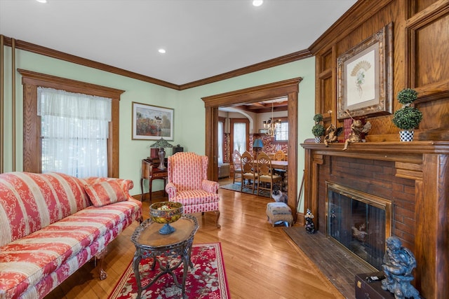 living room featuring light wood-style flooring, a fireplace, and ornamental molding