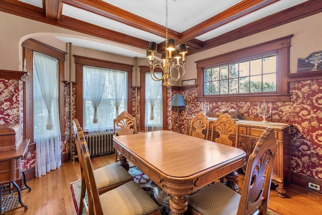 dining room featuring light wood finished floors, radiator, a chandelier, beamed ceiling, and wallpapered walls