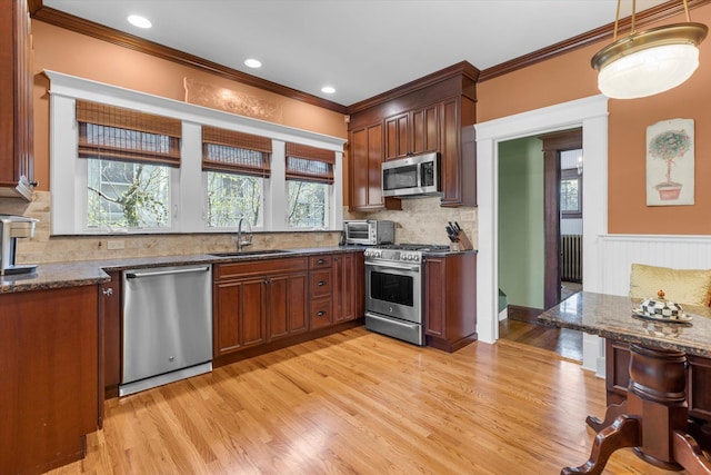 kitchen featuring backsplash, crown molding, stainless steel appliances, and a sink