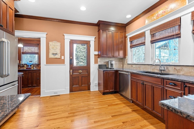 kitchen with light wood-style floors, crown molding, stainless steel dishwasher, and a sink