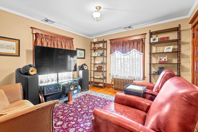 living area with crown molding, wood finished floors, visible vents, and radiator