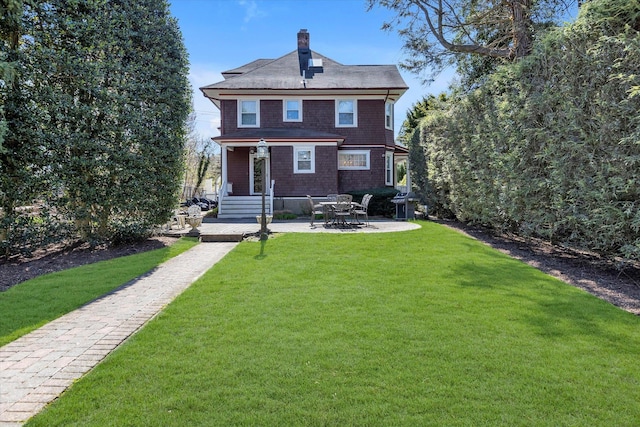 rear view of house featuring a patio area, a lawn, and a chimney