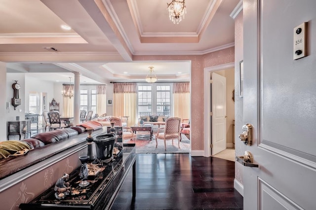 living area featuring a tray ceiling, an inviting chandelier, ornate columns, wood finished floors, and crown molding