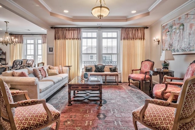 living room featuring an inviting chandelier, crown molding, and a raised ceiling