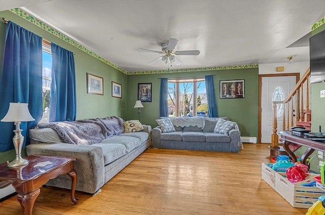 living area with baseboards, ceiling fan, baseboard heating, and light wood-type flooring